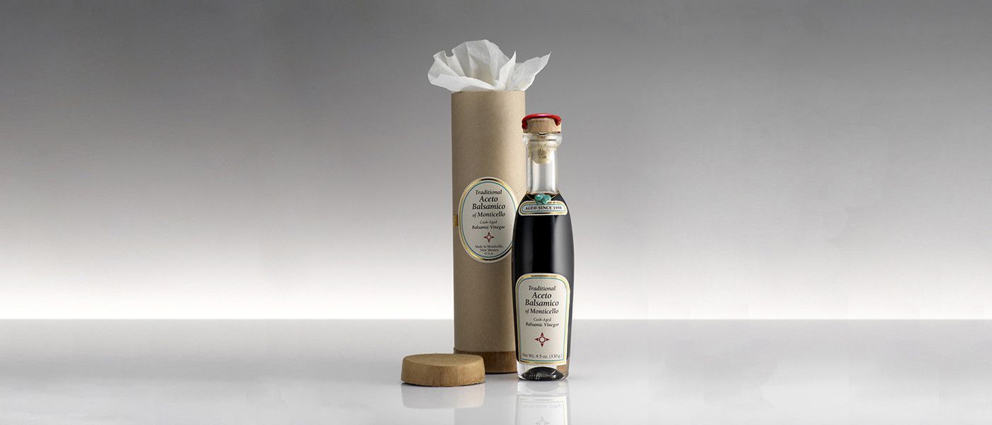 Traditional Aceto Balsamico of Monticello bottle beside its cylindrical gift packaging